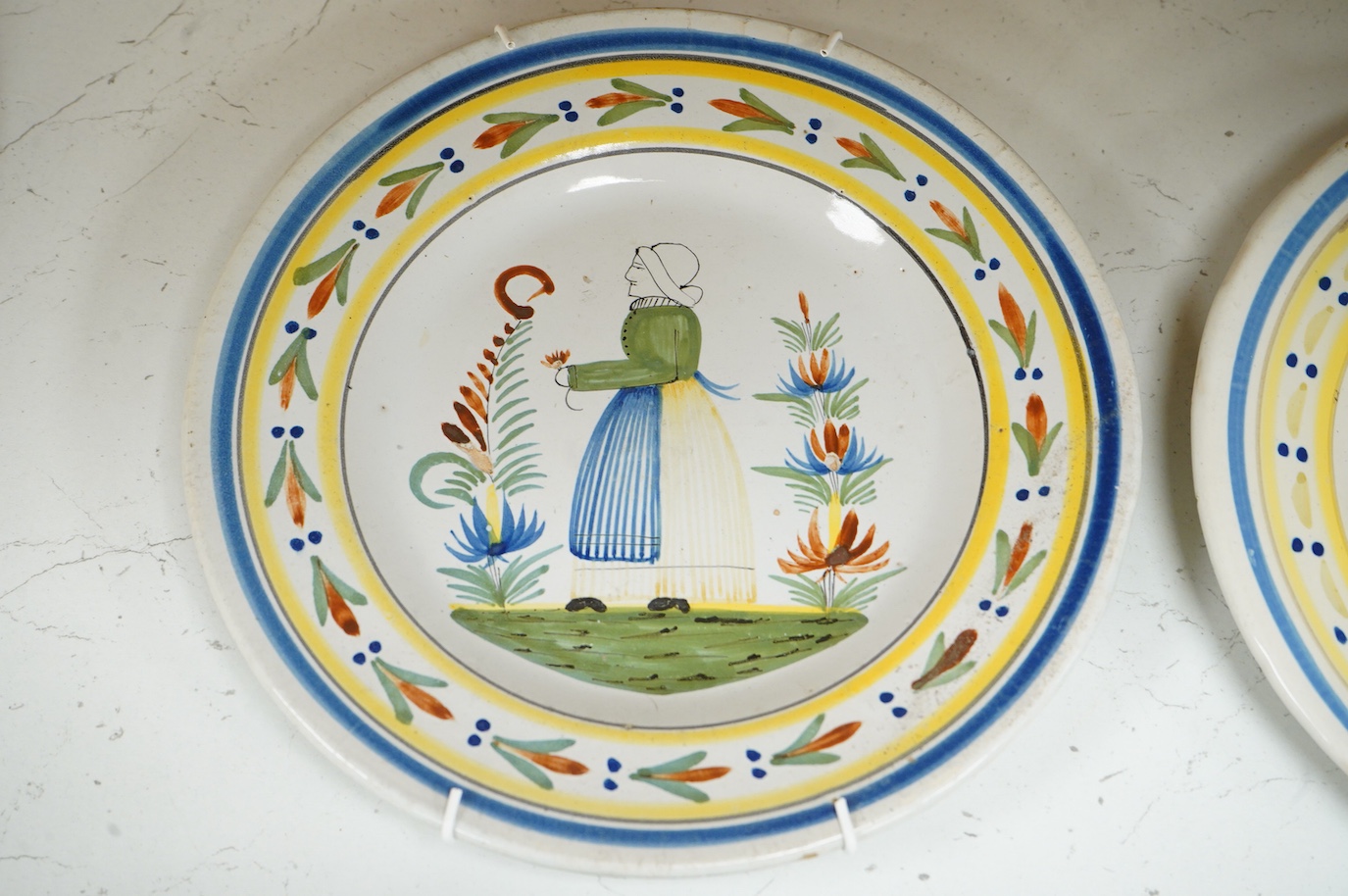 Four Quimper faience plates, each signed to the bases, 23cm in diameter